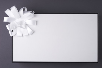 White gift box with ribbon on the gray background.Copy space.
