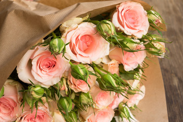 Bouquet of pink blooming fresh roses with buds on wooden table close up