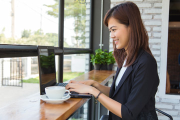 Happy young business woman on a coffee break using laptop computer in a cafe