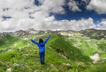 Freedom young traveler girl with hands up in mountains. Victory concept