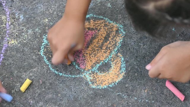 The child drawing a chalk on asphalt 
