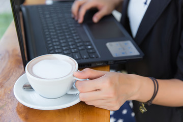 Young Asian woman wearing suit using laptop computer. Female working on laptop in an outdoor cafe