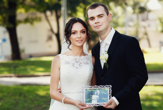 Adorable newlyweds are holding a picture in the frame