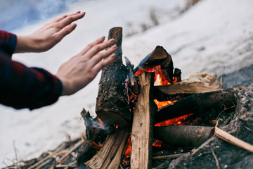 Girl warms hands near a fire in winter