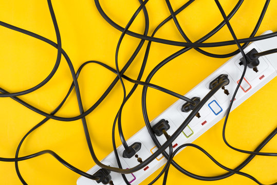 Top view of maximum electrical messy wire cords connected electrical power strip or extension block on colorful background