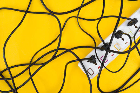 Maximum electrical cords connected electrical power strip or extension block  with messy wires, top view on colorful background, messy electric equipment flat lay concept.