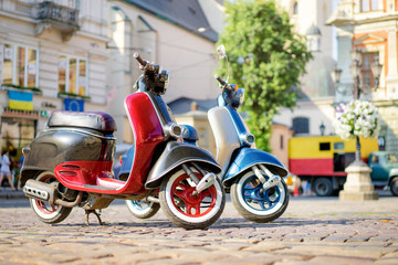 Naklejka premium Retro style. Two scooters on old town street.