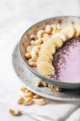 Healthy breakfast  berry smoothie bowl topped with banana, cashew and chia seeds, closeup