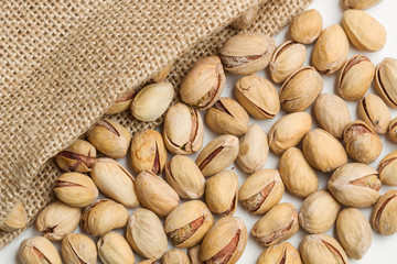 Pistachos con bolsa de arpillera sobre fondo blanco. Vista superior