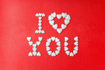The inscription I LOVE YOU made from white hearts on red leather background