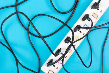 Maximum electrical cords connected electrical power strip or extension block  with messy wires, top view on colorful background, messy electric equipment flat lay concept.