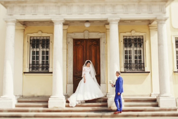 Naklejka premium Groom in blue suit walks to bride holding in his hands wedding b