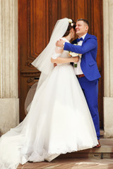 Groom in blue suit hugs bride tender holding her shoulders