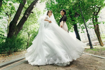 Bride whirls in her magnificent dress while bridesmaid stands be