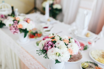 Look from above at little white and pink bouquets standing on wedding dinner table