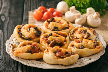 Pizza rolls with tomato sauce, bacon, mushrooms and cheese.