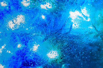 Fototapeta na wymiar Frozen ice crystals with beautiful blue colour below. Large and small trapped air bubbles all across the ice. 