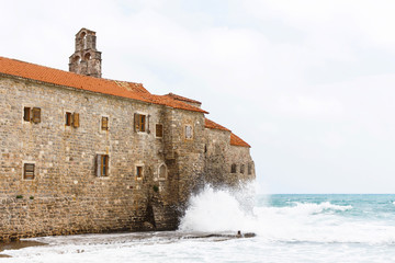 The view of budva old town, one of the best preserved medieval cities in the mediterranean, high waves on house, montenegro