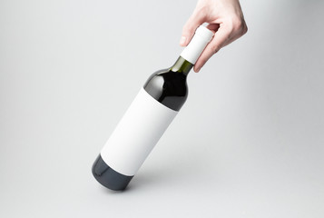 Hand is holding wine bottle on gray background
