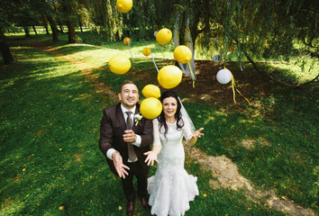 Joyful newlyweds are throwing lemons in the park