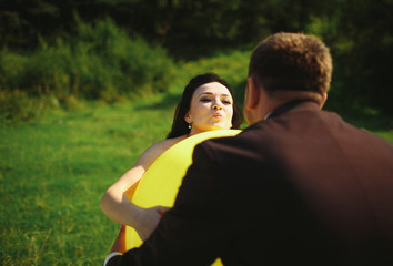 Ridiculous newlyweds are holding a yellow big balloon