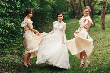 Funny bride and bridesmaids dance in the thick forest