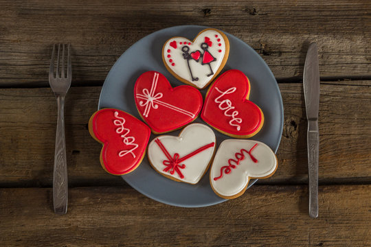 .Valentine cookies on a plate and cutlery on a wooden background