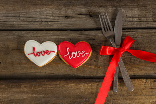 Valentine cookies and cutlery on a wooden background