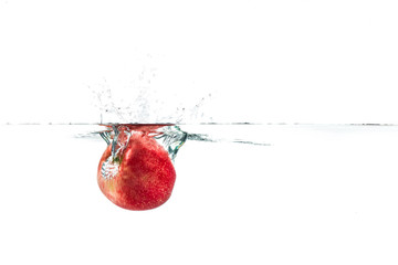 Fototapeta na wymiar Red apple dropped into the water with water splash on a white ba