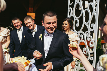 Smiling groom tastes wedding bread standing outside