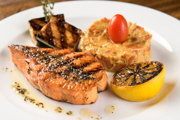Teriyaki salmon with zucchini and lemon on white plate