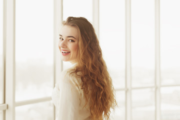 portrait of beautiful young woman with makeup posing by window