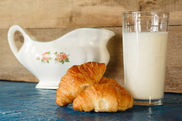 Croissants and glass of milk on wooden background