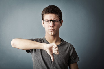 Teenager shows gesture thumb down, dislike, bad, disapproval, un