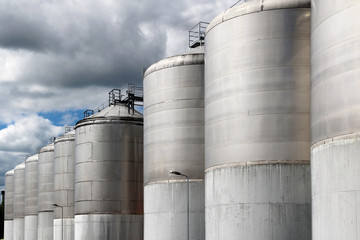large stainless steel fermentation vessel under cloudy sky