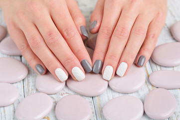 Woman hands with beautiful winter trend knit manicure and pebbles