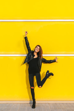 Cool trendy girl posing over a yellow wall
