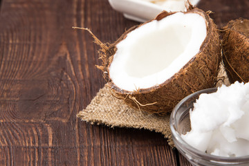 Coconut with coconut oil in jar on wooden background