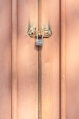Closeup the metal padlock fasten on old rusty metal entrance doo