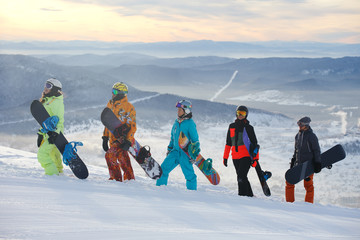 Group of friends snowboarders having fun on the top of mountain