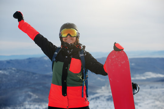 Beautiful young girl with a snowboard and his hand raised