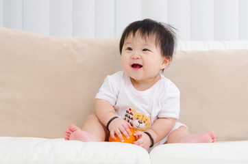 Fototapeta premium Asian baby sitting on sofa