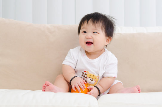 Asian baby sitting on sofa