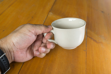 ceramic cup in hand with wooden table background.