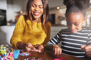 Fototapeta premium Smiling woman working with child on bead project