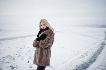 Portrait of young elegance blonde girl in a fur coat background