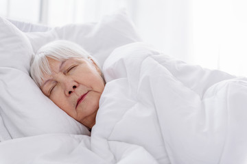 Serene old woman keeping to bed in hospital