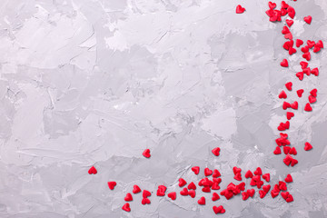 Many little  decorative red hearts on textured grey background.