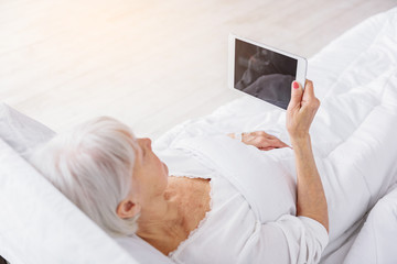 Cool old patient watching at tablet in hospital room