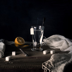 rustic still life. Tea with lemon in a large circle on the wooden table. black background